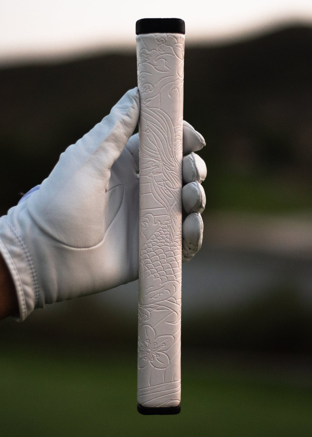Kaiyen Pearl white koi-engraved putter grip held in a gloved hand